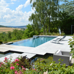 Piscine à débordement 11m x 5m x1.50m avec volet immergé et escalier plage toute largeur Plages en pierres naturelles et bois exotique