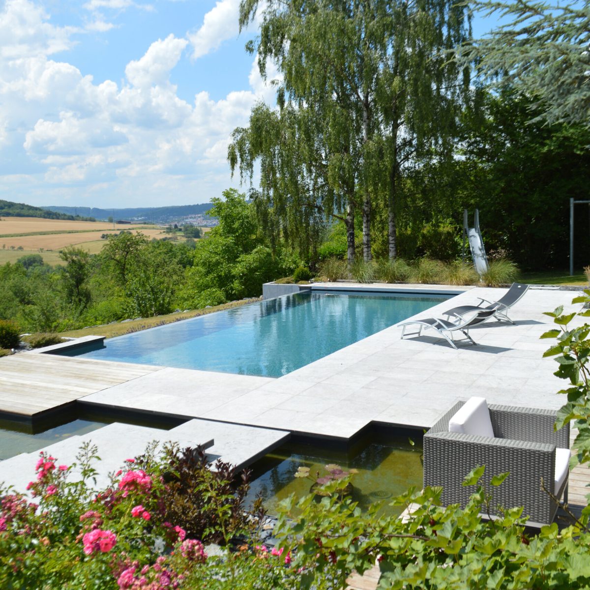 Piscine à débordement 11m x 5m x1.50m avec volet immergé et escalier plage toute largeur Plages en pierres naturelles et bois exotique