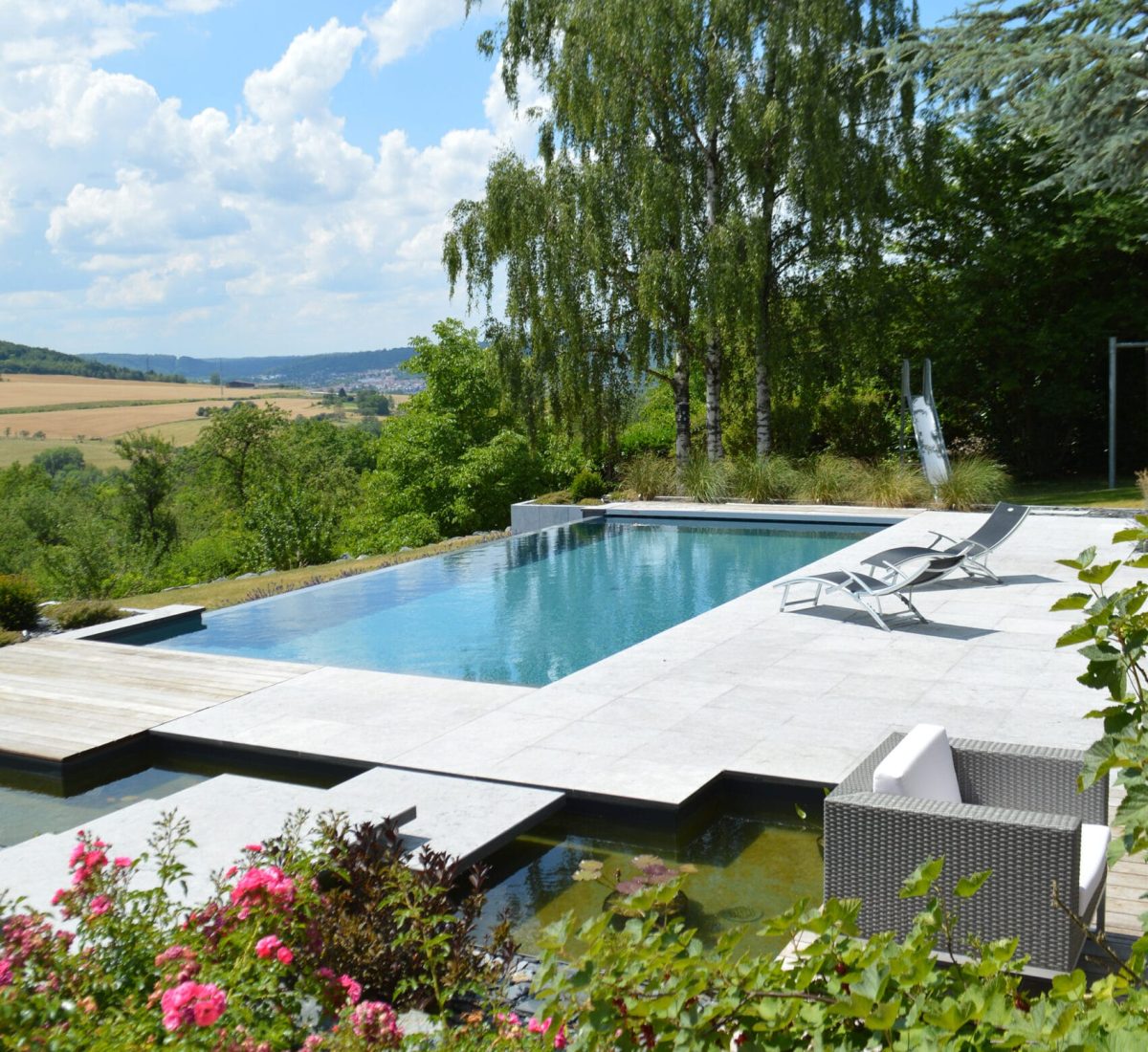 Piscine à débordement 11m x 5m x1.50m avec volet immergé et escalier plage toute largeur Plages en pierres naturelles et bois exotique