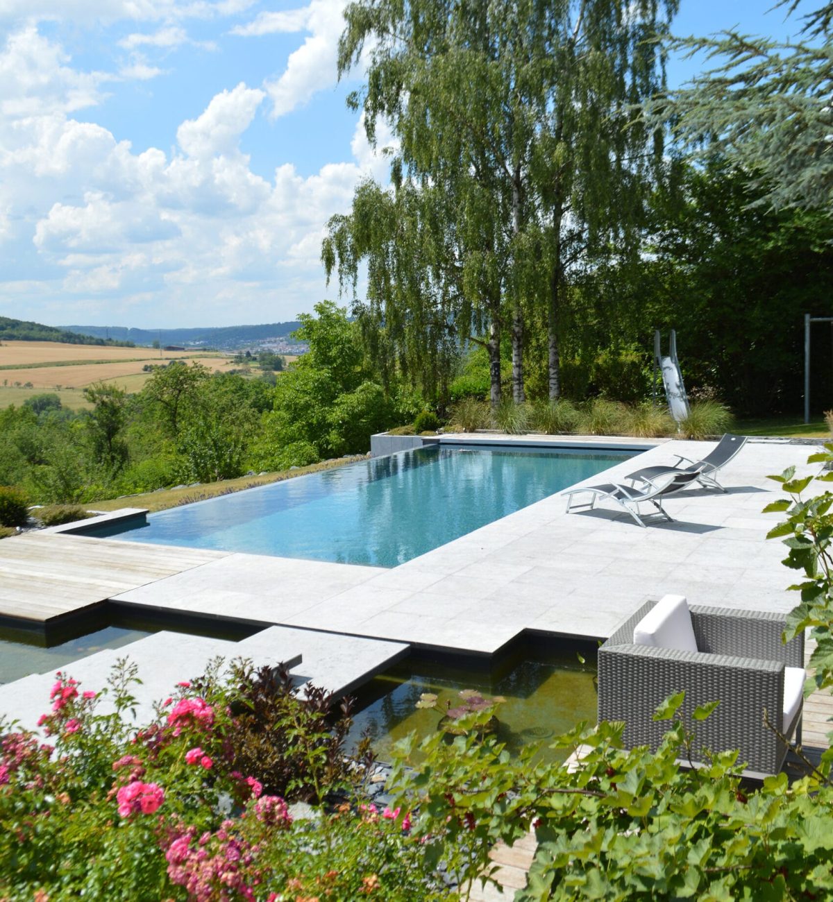 Piscine à débordement 11m x 5m x1.50m avec volet immergé et escalier plage toute largeur Plages en pierres naturelles et bois exotique