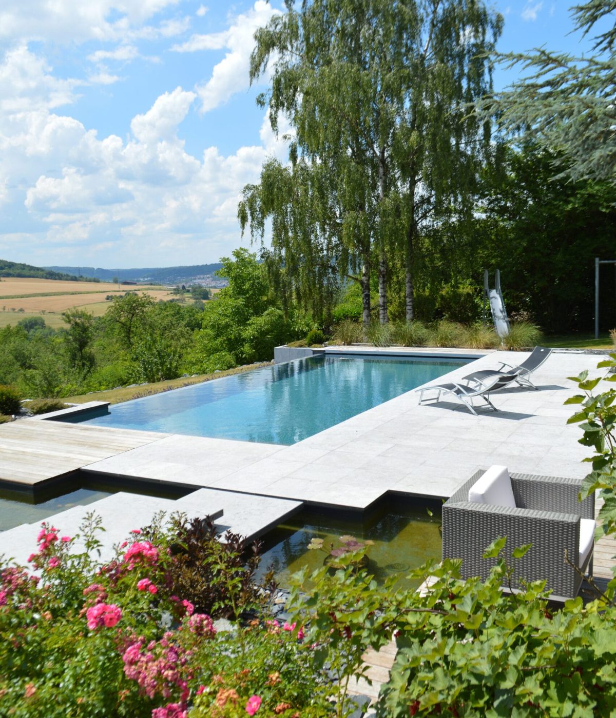 Piscine à débordement 11m x 5m x1.50m avec volet immergé et escalier plage toute largeur Plages en pierres naturelles et bois exotique